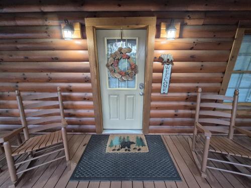 een voordeur van een blokhut met twee banken bij Black Bear Retreat 2 beds! cabin in Glade