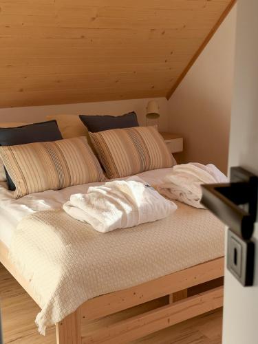 a bed with white sheets and pillows in a room at Domki przy Lesie Sasino in Sasino