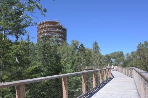 a wooden pedestrian bridge with a tall building in the background at Condo familial Mont Blanc, accès ski in Ski out in Saint-Faustin