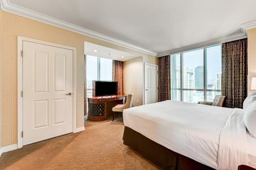 a bedroom with a bed and a desk with a television at The Signature at MGM Grand, Luxury Balcony Suite, Strip View in Las Vegas