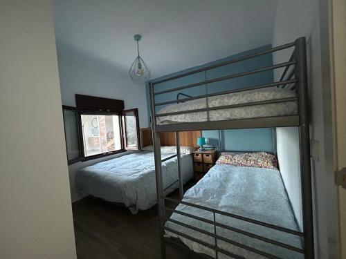 a bedroom with two bunk beds and a window at Casa del arroyo in Caserío Arroyofrío