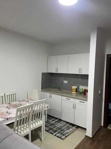 a kitchen with white cabinets and a table and a dining room at Apartment in Kosovo Polje