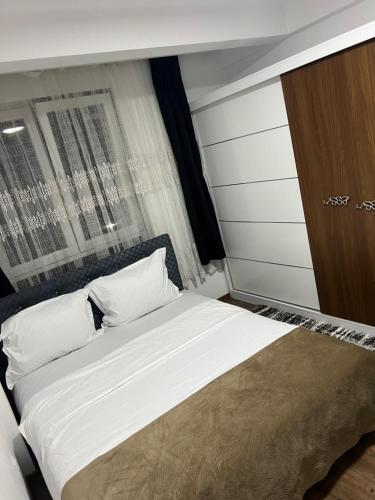 a bed with white sheets and pillows in a room at Apartment in Kosovo Polje