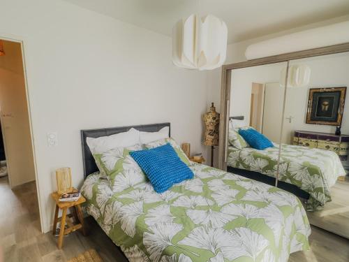 a bedroom with a bed with blue pillows and a mirror at Le Cosy Chic - F2 in Carrières-sous-Poissy