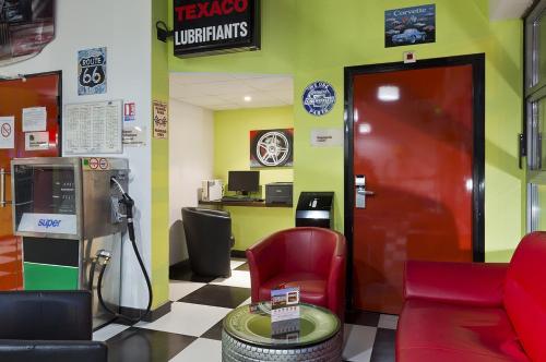 ティオンヴィルにあるEnzo Hotels Thionville by Kyriad Directの赤い椅子と公衆電話のある待合室