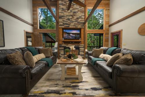 uma sala de estar com sofás de couro e uma mesa em Wine Time 5 Bedroom Shuffleboard Hot Tub Fire Pit Play Set em Broken Bow