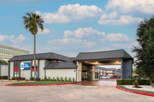 a building with a palm tree in front of it at Best Western Webster Hotel, NASA in Webster