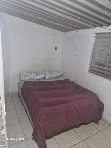 a bedroom with a bed in a white room at Recanto do Leâo in Guarujá