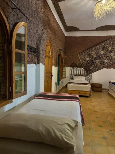 a bedroom with two beds and a window at Kasbah Azalay Merzouga takojt in Merzouga