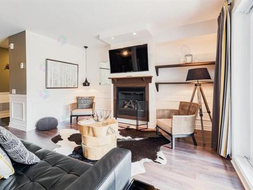 a living room with a couch and a fireplace at 2 bedroom condo Ski in Ski out Sommets St-Sauveur in Saint-Sauveur-des-Monts