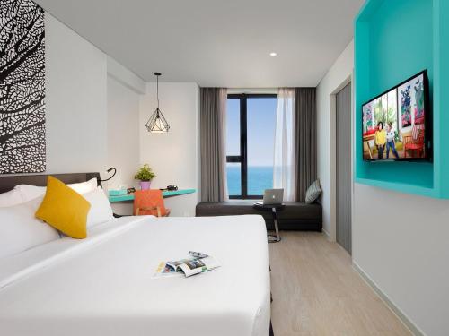 a bedroom with a large white bed and a living room at ibis Styles Nha Trang in Nha Trang