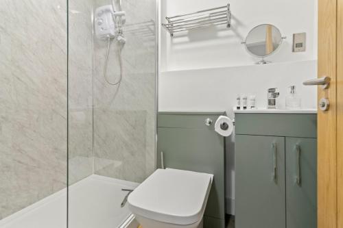 a bathroom with a toilet and a glass shower at Pear Tree - Stylish City Centre Apartment in Worcester