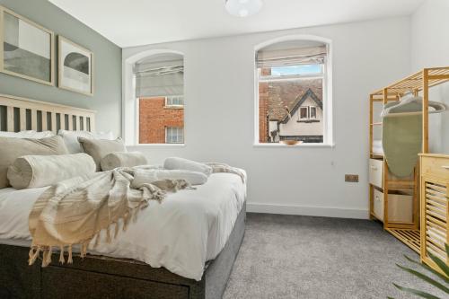 a white bedroom with a bed and two windows at Pear Tree - Stylish City Centre Apartment in Worcester