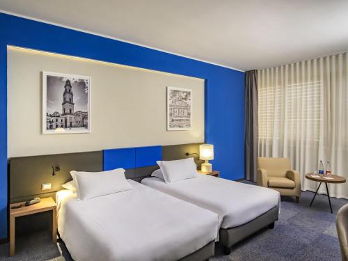 two beds in a hotel room with blue walls at Mercure Hotel President Lecce in Lecce