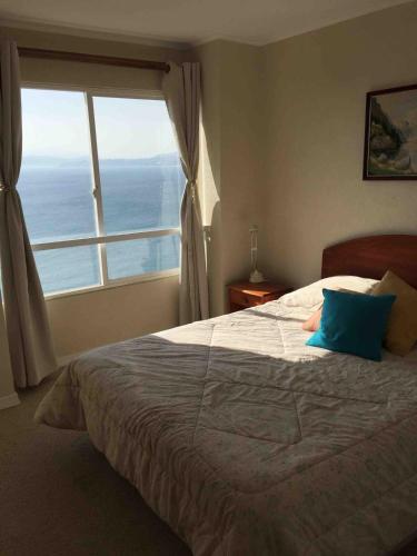 a bedroom with a large bed with a large window at Ocean View Apartment in Family Complex in Puchuncaví