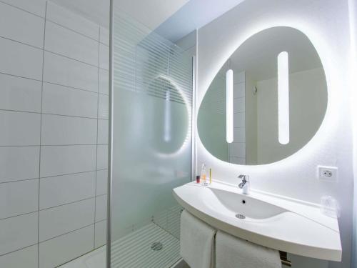 a white bathroom with a sink and a mirror at ibis budget Montpellier Sud Près d'Arènes in Montpellier