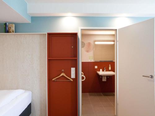 a bathroom with a red door and a sink at greet Wien City Nord in Vienna