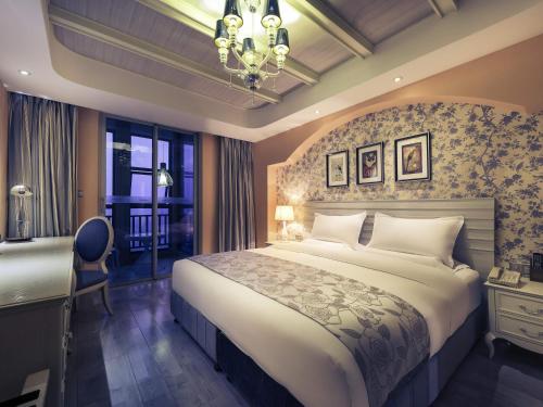 a bedroom with a large bed and a chandelier at Mercure Xiamen Exhibition Centre in Xiamen
