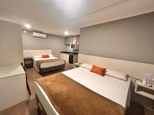 a hotel room with two beds and a kitchen at Terrazas Hotel in Curitiba