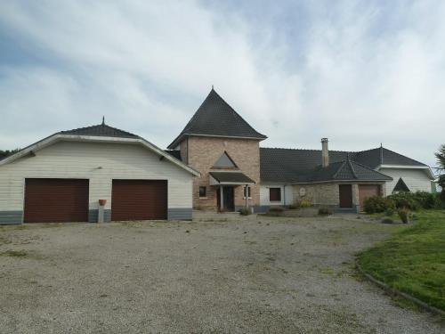 a large house with two garages in a yard at Gîte du Tronquoy in Aix-en-Ergny