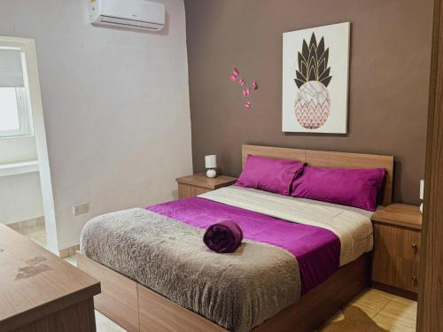 a bedroom with a bed with purple sheets and a pineapple picture at Modern 4-Bedroom Villa with Private Pool & 2 Baths in Taʼ Ċantar