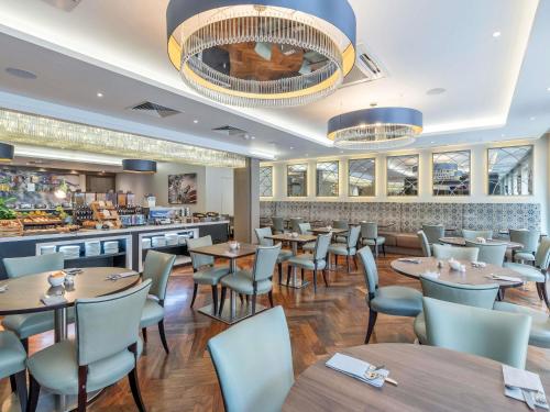 a restaurant with tables and chairs and a bar at Mercure Edinburgh Haymarket in Edinburgh