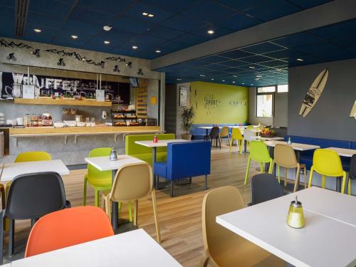 a restaurant with white tables and colorful chairs at ibis budget Toulouse Centre Gare in Toulouse