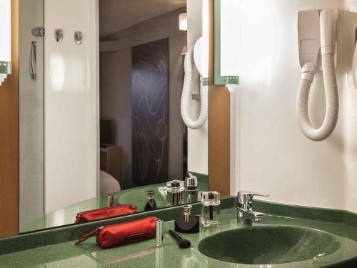 a bathroom with a green sink and a mirror at ibis Auch in Auch