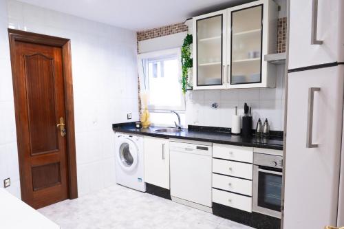a white kitchen with a washer and dryer in it at La Casa de los Osorios in León