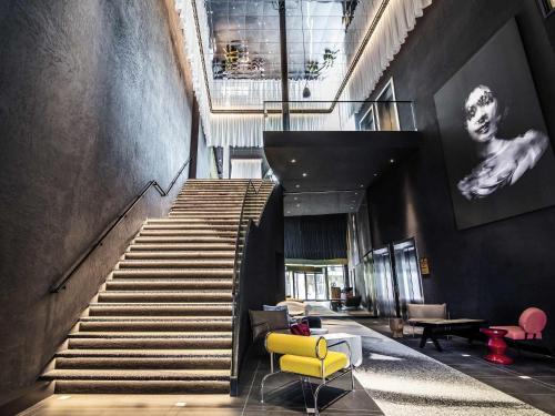 a staircase with a yellow chair in a lobby at Tribe Amsterdam City in Amsterdam