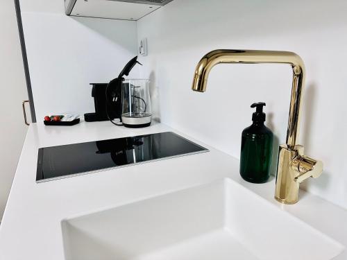 a kitchen sink with a gold faucet and a bottle of soap at Katariina Apartments in Kotka