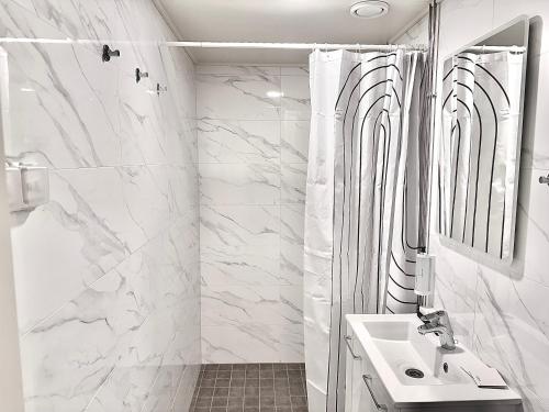 a white bathroom with a shower and a sink at Katariina Apartments in Kotka