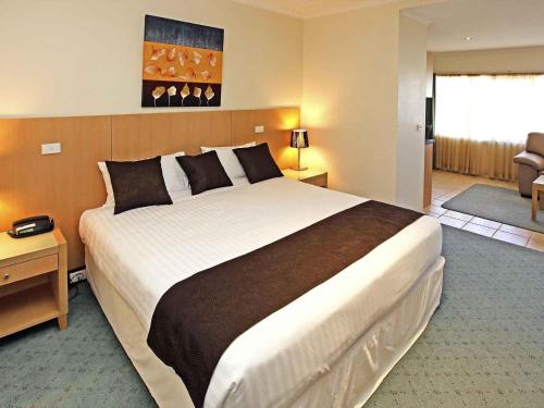 Un dormitorio con una cama grande en una habitación de hotel. en Mercure Hotel Mildura, en Mildura