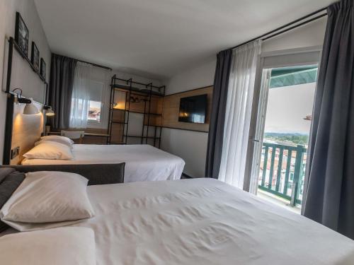 a hotel room with two beds and a window at ibis Ciboure Saint-Jean-de-Luz in Ciboure