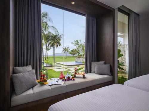 una camera da letto con due letti e una grande finestra di Pullman Lombok Merujani Mandalika Beach Resort a Kuta Lombok