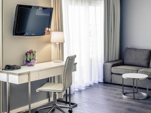 a room with a desk with a tv and a chair at Mercure Hotel Raphael Wien in Vienna