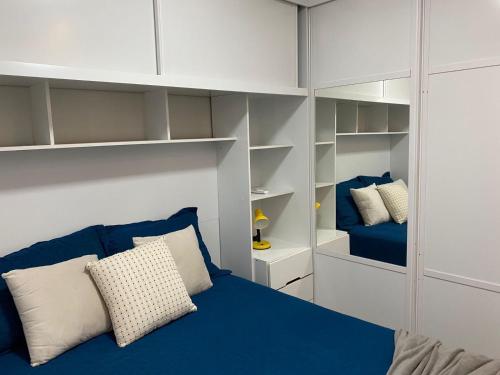 a bedroom with a blue bed and white shelves at Apartamento Proximo ao Salvador Shopping in Salvador