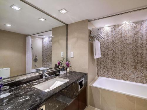 a bathroom with a sink and a tub and a mirror at Novotel Beijing Peace in Beijing