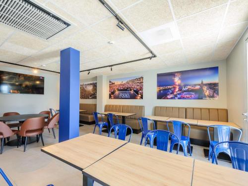 a waiting room with tables and blue chairs at Ibis Budget La Rochelle Puilboreau in Puilboreau