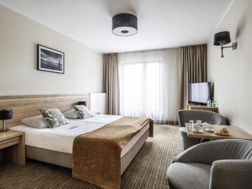 a hotel room with a bed and a chair at Mercure Wiazowna Brant in Wiązowna