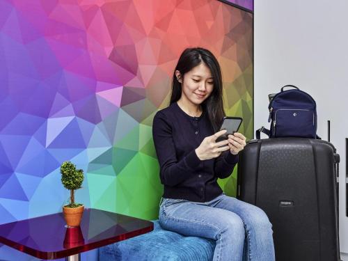 a woman sitting next to a table with her cell phone at ibis budget Singapore Ametrine in Singapore