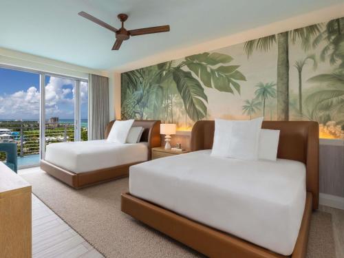 a bedroom with two beds and a painting of palm trees at SLS at Baha Mar in Nassau