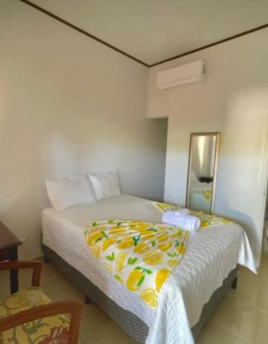a bedroom with a bed with a yellow blanket on it at Hotel Boutique las Colinas in San José de Colinas