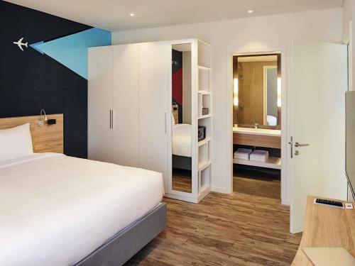 a bedroom with a white bed and a bathroom at Ibis Saigon Airport in Ho Chi Minh City