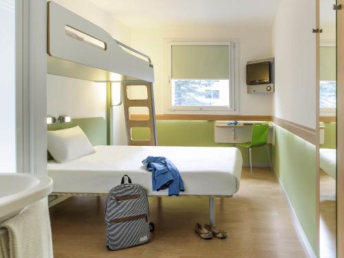 a small room with a bed and a backpack at ibis budget Metz Sud in Augny