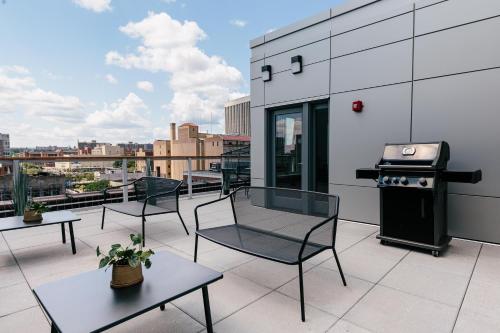 ein Balkon mit Stühlen und einem Grill auf einem Gebäude in der Unterkunft Kislak 404 Luxurious 1BR in Heart of Downtown in Newark