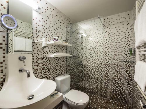a bathroom with a white sink and a toilet at Mercure Hotel Berlin Zentrum Superior in Berlin