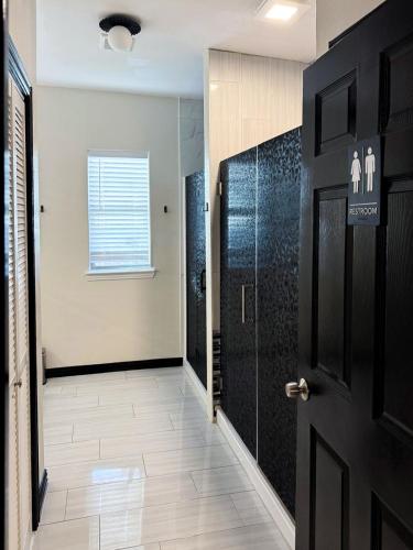 a hallway with a black door and a tile floor at Bishop Hostel in Dallas