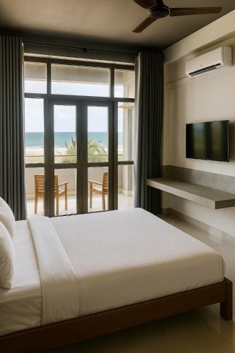 a bedroom with a bed and a view of the ocean at Trident Sea Hotel in Negombo