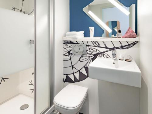 Un baño blanco con lavabo y espejo. en ibis budget Clermont Ferrand Sud, en Aubière